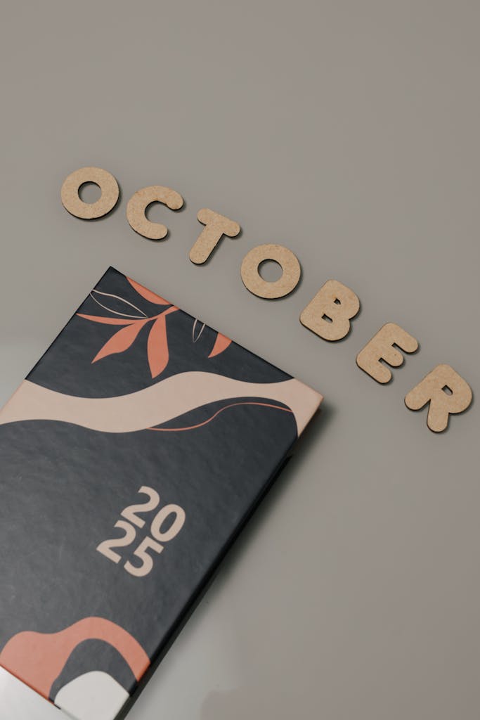 Flat lay of 2025 planner and October letters on beige surface.