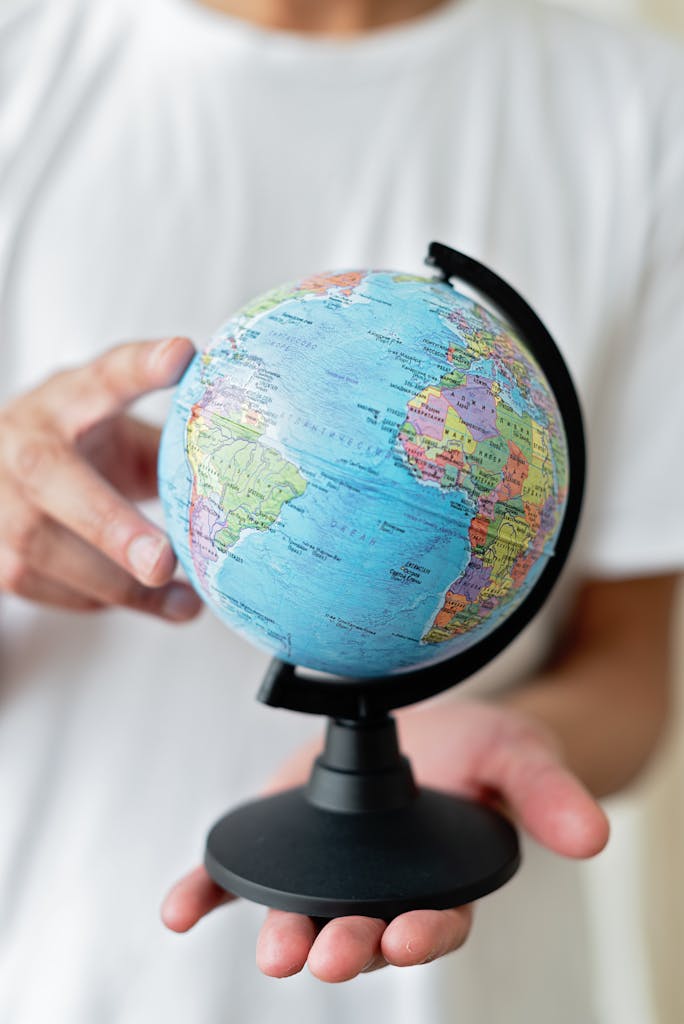 Person holding a small globe with focus on the Americas. Educational and travel concept.